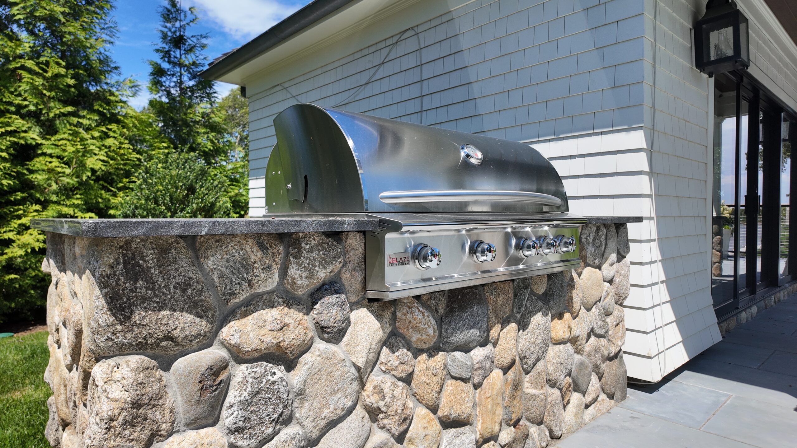 Outdoor kitchen with stone grill surround on Cape Cod